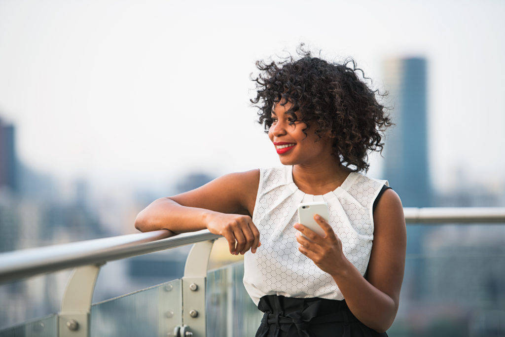 A businesswoman with smartphone standing against London view panorama