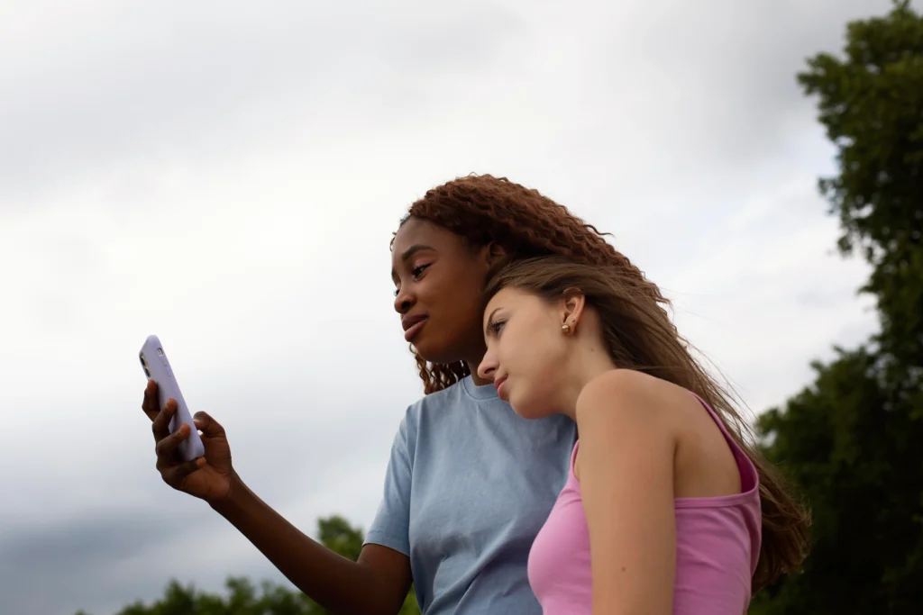 teenage friends using smartphone outdoors