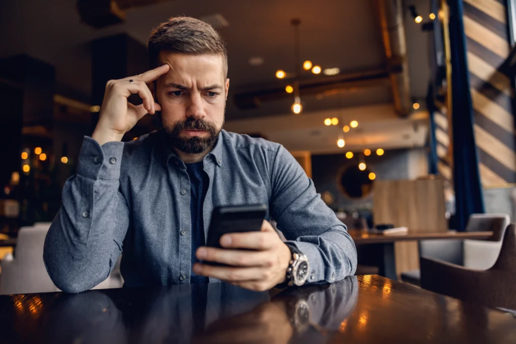 upset man is sitting cafe looking phone